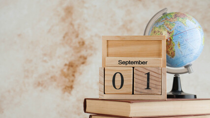 Wooden calendar September 1 on a stack of books, globe. Concept for Knowledge Day, beginning of school year. Copy space.