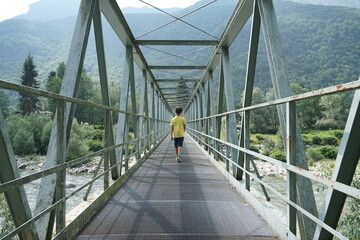 child walking on a suspension bridge over the river
