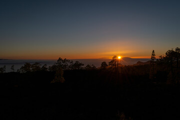 Puesta de sol con árboles y montañas