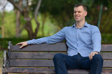 Naklejka na ściany i meble Portrait of happy businessman relaxing at the park