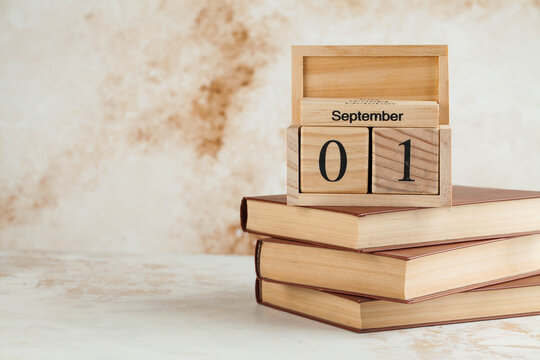 Wooden calendar September 1 on a stack of books. Concept for Knowledge Day, beginning of school year. Copy space.