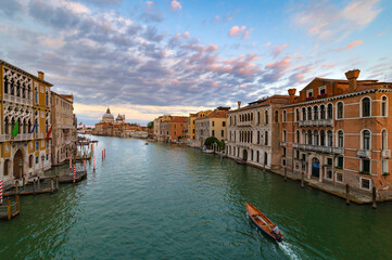 A wonderful evening shot of the Canal Grande seen from the Ponte dell'Accademia. On the background the church of Santa Maria della Salute. Sunset with pink and blue clouds, green water. Venice, Italy.