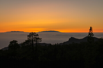 Puesta de sol con árboles y montañas