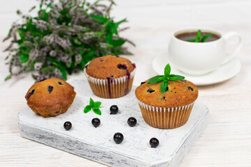 Cupcakes with black currant and mint leaves on a white plate. Selective focus.