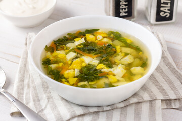 Nettle soup with eggs and sour cream on a white wooden table