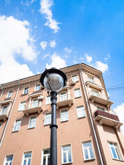 street lantern and apartment house under blue sky with white clouds on sunny summer day on Malaya Nikitskaya street in Moscow city
