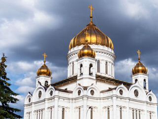 Fototapeta na wymiar view of Cathedral of Christ the Saviour from west side under dark gray rainy clouds in Moscow city in sunny summer evening