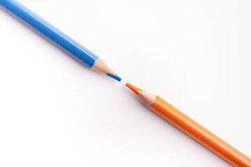Two diagonal pencils with sharpened tips in complementary colors, blue and orange. On a white background. back school objects