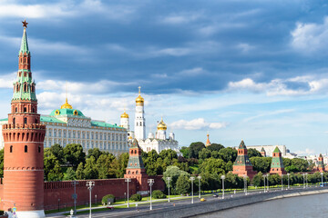 Fototapeta premium view of Kremlin with embankment of Moskva River under dark blue rainy clouds during city sightseeing tour on excursion bus in Moscow city on sunny summer day