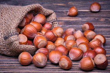 Hazelnuts in bag, vegetarian food in wooden bowls, on old wooden background