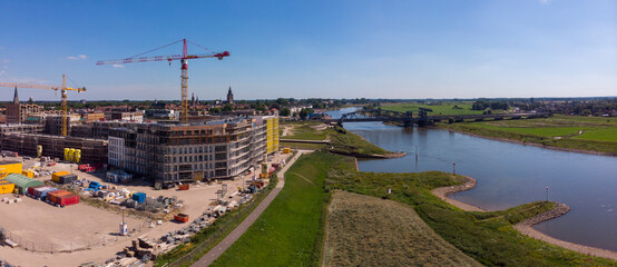 Fototapeta na wymiar Wide aerial panoramic view on a construction site of the new Noorderhaven neighbourhood on the left and river IJssel that flows passed Hanseatic Dutch city of Zutphen on the right