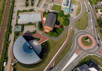 Contemporary modern geometric and circular design architecture office building flanked by traffic roundabout and train tracks seen from above