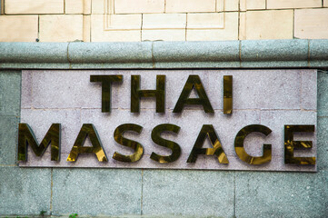 Thai massage golden reflective and shiny signboard on a stone facade