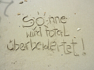 Sonne wird überbewertet-witziger Spruch in Sand gemalt am Meer