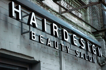 Obraz premium Hair design sign on a facde in form of 3d ads. Beauty salon signboard. Beauty parlour facade plate