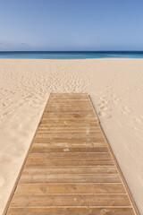 Vertical photograph of Corralejo beach in Fuerteventura with wooden access in the foreground and no one