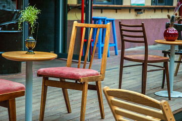 European cafe in summer outdoor patio. Summer terrace with vintage wooden chair and table. Reastaurant tables waiting for customers at an outdoor terrace