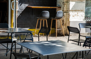 Fototapeta na wymiar Summer terrace with modern metallic chairs and tables. Reastaurant tables waiting for customers on city street