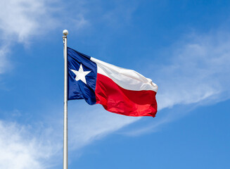 Texas State flag on the pole waving in the wing against blue sky and white clouds - 368332210