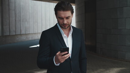 Businessman using smartphone outside. Worker browsing internet online on street