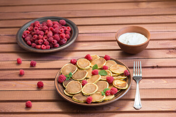 Fototapeta premium Pancake cereals and red ripe fresh raspberries in a brown plate on a wooden table. Delicious Breakfast