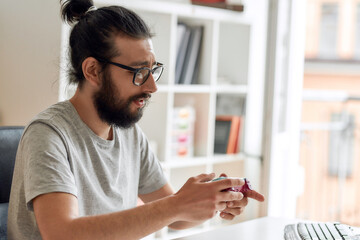 Male technology blogger in glasses looking at game controller joystick, holding it while recording video blog or vlog about new gadgets at home