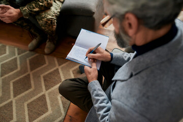 Writing in notebook. Close up of hands of psychologist making notes while communicating with...