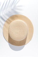 Minimal summer vacation vertical concept. Palm leaf shadow over a straw hat