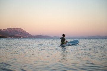 Naklejka premium Boy sitting on the rear end of sup board