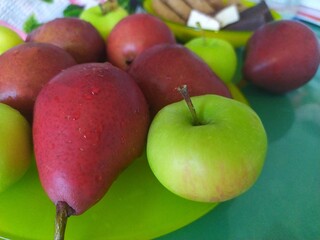 Dark red pears green apples and cookies on a yellow plate
