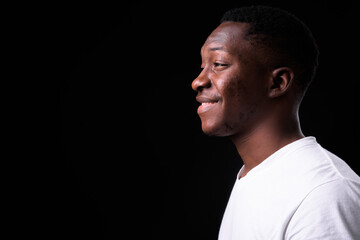 Obraz premium Happy young handsome African man against black background