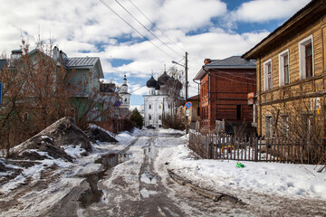 Fototapeta na wymiar Dirty spring road to orthodox church in russian villiage