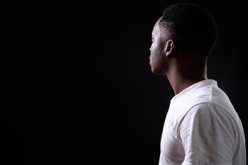 Young handsome African man against black background