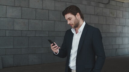 Business man typing on smartphone at street. Excitement guy celebrating success