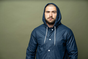 a man stands in a blue rain jacket looking at the camera