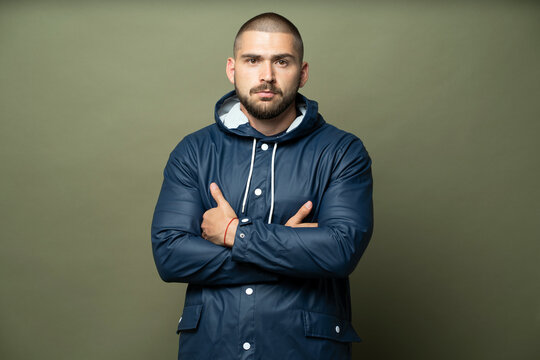 A Man Stands In A Blue Rain Jacket Looking At The Camera