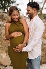 Portrait cheerful pregnant couple looking to each other in the park