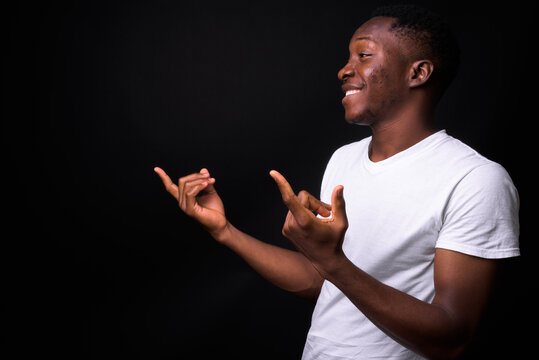 Happy Young Handsome African Man Against Black Background