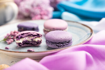 Purple macarons or macaroons cakes with cup of coffee on a white concrete background. Side view, selective focus.