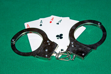 A pair of handcuffs on playing cards ,  on green table