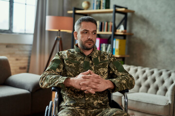 Thoughts. Middle aged military man in a wheelchair looking thoughtful aside during therapy session....
