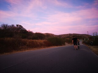 Obraz premium sunset on the road with boy walking on longboard