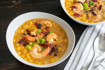 Sweet Corn, Peppered Bacon, and Shrimp Chowder: Bowls of seafood chowder with vegetables and bacon garnished with green onions