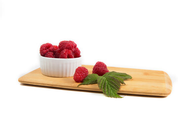 Ripe tasty bright Fresh raspberry in a wicker basket on a cutting board