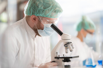 A scientist using a microscope in a laboratory to view a blood sample.