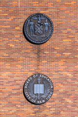 Insignia of the Deparment of Education on the wall of a Bronx public school building, New York, NY