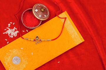 Raksha Bandhan concept - Rakhi and other props arranged on a red satin background.