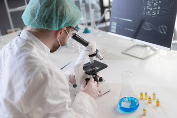 A scientist using a microscope in a laboratory to view a blood sample.