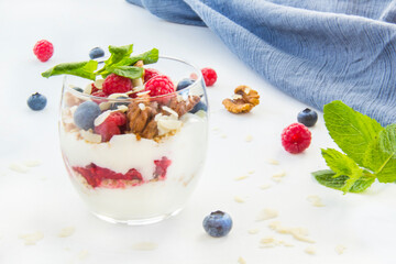 Healthy blueberry, raspberry and walnut parfait in a glass on a white background