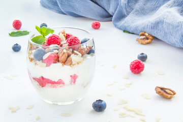Healthy blueberry, raspberry and walnut parfait in a glass on a white background